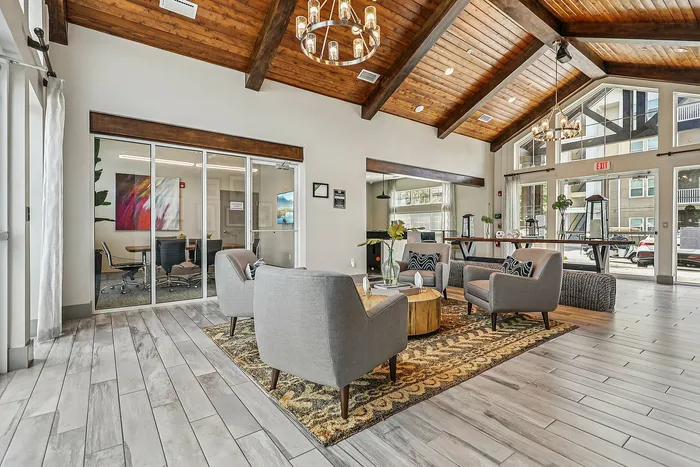 Chic apartment lobby with stylish seating, modern art, and wooden vaulted ceilings, offering a warm and inviting atmosphere.