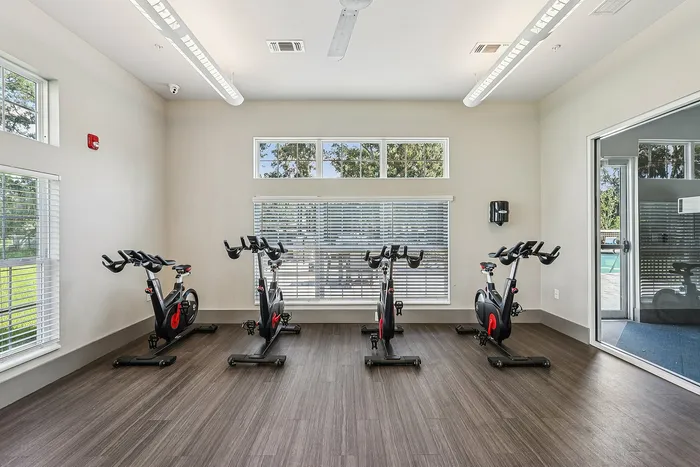 Bright and inviting fitness room featuring state-of-the-art stationary bikes, large windows, and modern wood flooring.