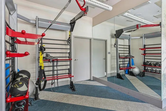 Modern fitness room with versatile equipment, wall-to-wall mirrors, and vibrant design details.