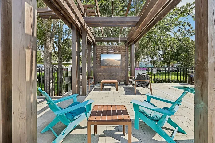 Inviting outdoor patio with modern wooden pergola, vibrant turquoise seating, and lush garden views, perfect for relaxation.