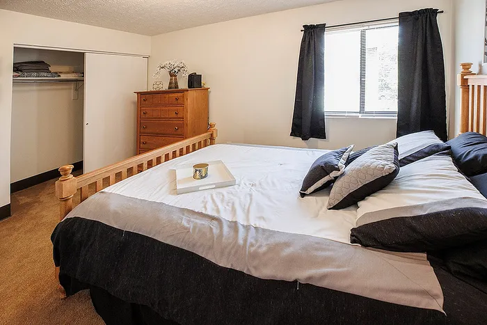 Cozy bedroom with natural light, featuring a comfortable bed, stylish dresser, and an open closet.