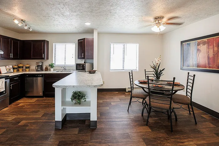 Modern kitchen with dark wood cabinets and island adjacent to an elegant dining area featuring stylish decor and warm lighting.