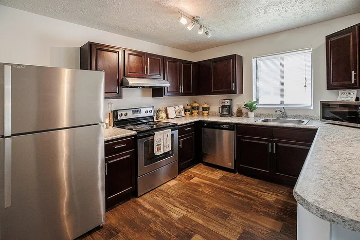 Modern kitchen with sleek stainless steel appliances, rich wooden cabinetry, and elegant countertops, offering a warm and inviting atmosphere.