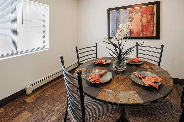 Inviting dining room with a stylish stone tile table, accented by vibrant orange napkins and elegant decor in an intimate setting.