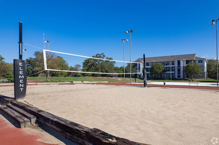 Inviting sand volleyball court with clear blue skies and modern apartment complex in the background, perfect for outdoor recreation.