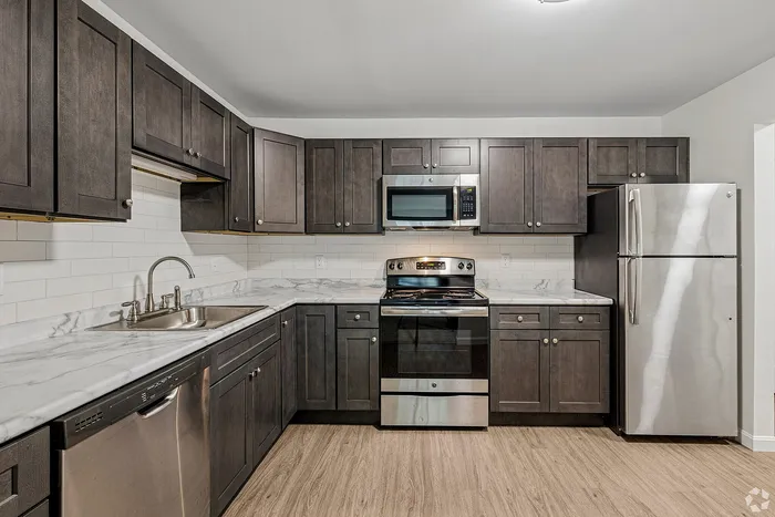 Modern kitchen featuring sleek dark wood cabinets, stainless steel appliances, and elegant marble countertops.