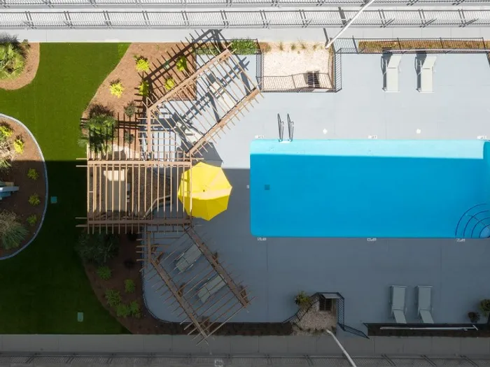 Aerial view of the pool and sundeck area with shaded pergolas and lounge chairs at Legacy Student Living near FSU in Tallahassee, FL
