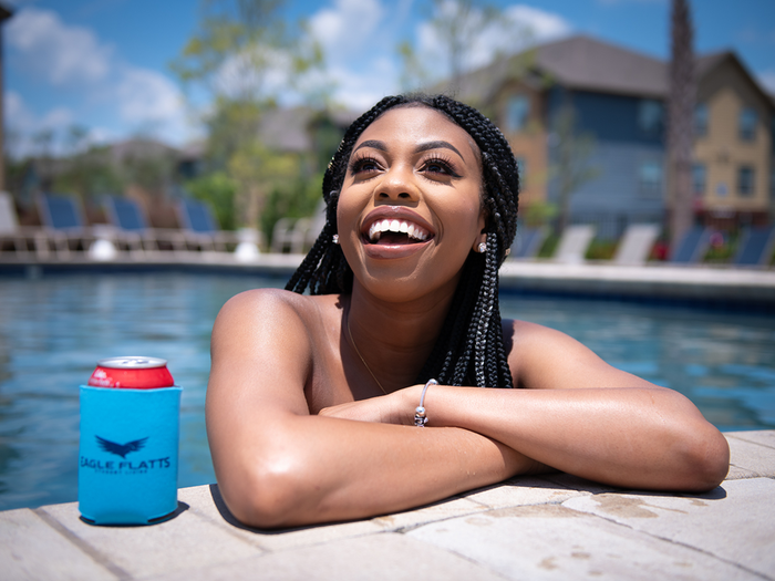 Resident enjoying the resort-style pool at Eagle Flatts Apartments in Hattiesburg, MS with branded drink cooler.