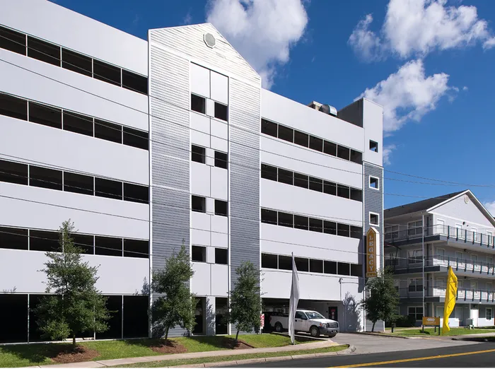 Exterior view of the Legacy Student Living apartment building and parking garage in Tallahassee, FL, near FSU, offering convenient on-site parking for residents