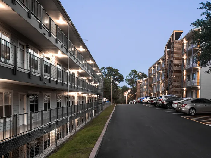 Evening view of the well-lit exterior walkways and parking area at Legacy Student Living apartments near FSU in Tallahassee, FL