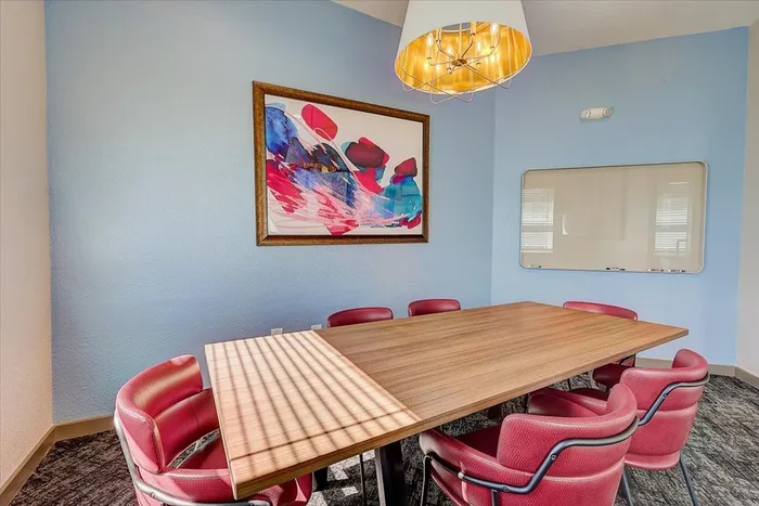 Private meeting room with a large table, vibrant artwork, and a whiteboard at The Preserve Murfreesboro.