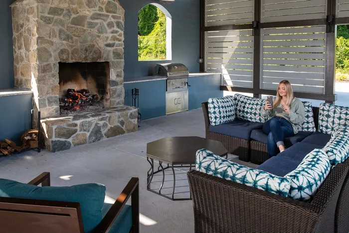 Outdoor lounge with comfy seating, grilling area, and stone fireplace at The Flatts Salisbury
