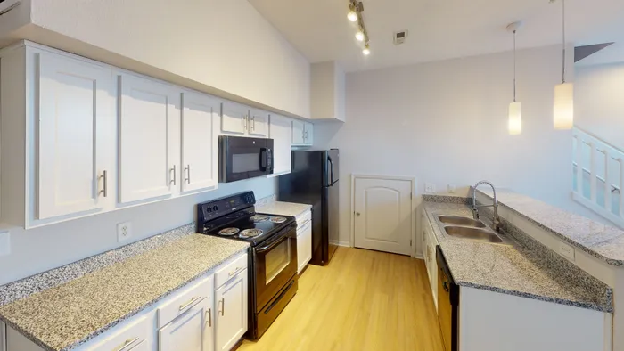 A sleek, modern kitchen at Ralston Apartments in Downtown Indianapolis, featuring granite countertops, white shaker cabinets, and black appliances for a stylish and functional cooking space.