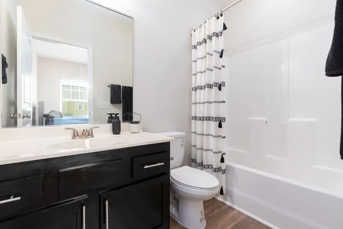 Modern bathroom with dark vanity and shower at Seaglass Apartments in Corpus Christi