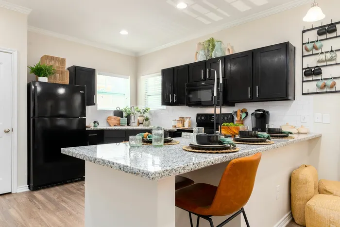 Kitchen with black appliances, black cabinets, and a breakfast bar at Seaglass Apartments in Corpus Christi