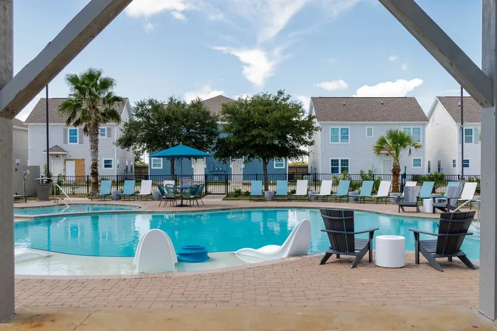 Resort-style pool with lounge chairs and shaded seating at Seaglass Apartments in Corpus Christi