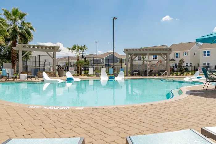 Resort-style pool with lounge chairs and shaded areas at Seaglass Apartments in Corpus Christi