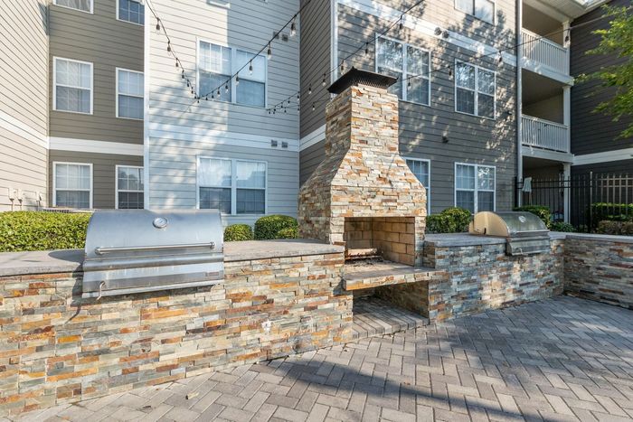 Outdoor kitchen with stone counters, BBQ grills, and wood-fired oven at Theater Street Apartments in Lafayette, LA