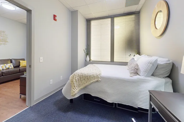 Comfortable bedroom with carpet flooring in University Plaza student apartments near NIU