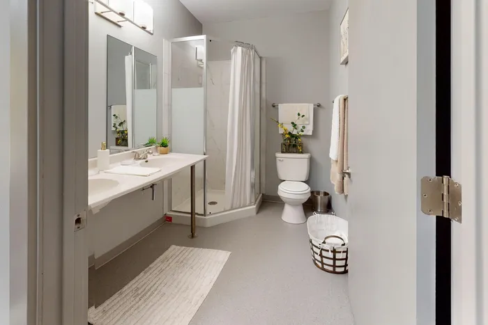 Spacious A4 bathroom featuring dual sinks and a tiled shower in University Plaza off-campus apartments near NIU