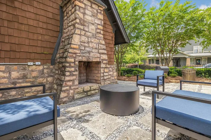 Cozy outdoor seating area with a stone fireplace at The Cottages of Hattiesburg, perfect for relaxing and socializing in the community.