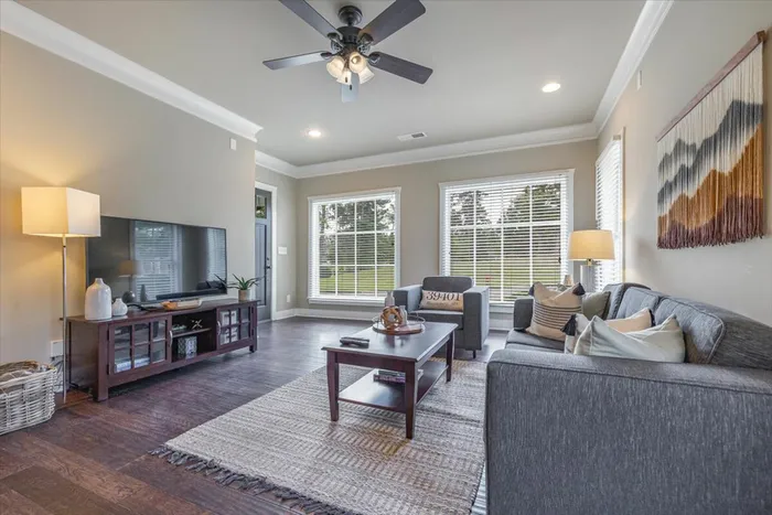 Bright and airy living room at The Cottages of Hattiesburg featuring large windows, comfortable seating, and modern decor, perfect for student relaxation and entertaining.