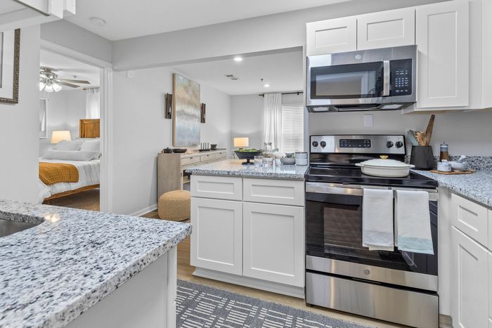 Kitchen with white cabinets and grey granite counters at Theater Street Apartments in Lafayette, LA