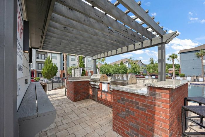 Outdoor grilling station by the pool at Eagle Flatts Apartments in Hattiesburg, MS with stainless steel grills.
