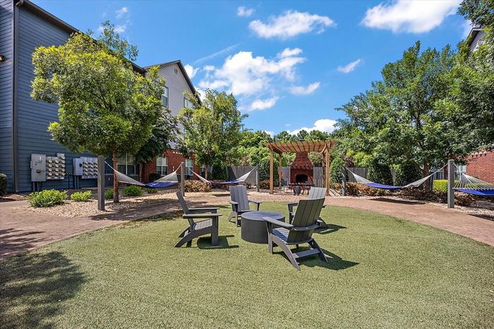 Outdoor lounge area with fire pit, hammock garden, and seating at Eagle Flatts Apartments in Hattiesburg, MS.