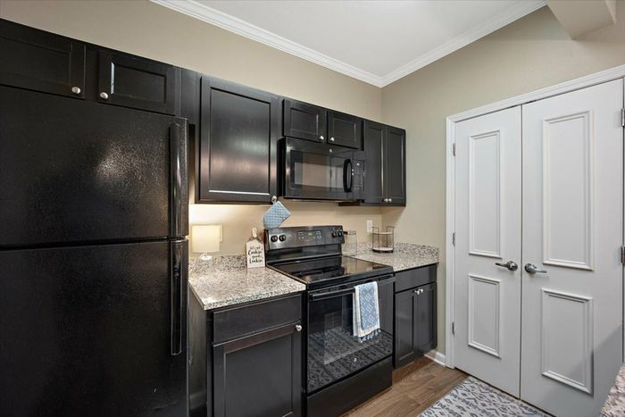 Modern kitchen at Eagle Flatts Apartments in Hattiesburg, MS with black appliances and granite countertops.