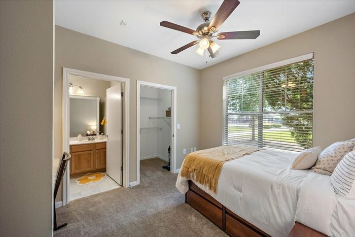 Bedroom with ceiling fan, large window, and private en-suite bathroom at Eagle Flatts Apartments in Hattiesburg, MS.