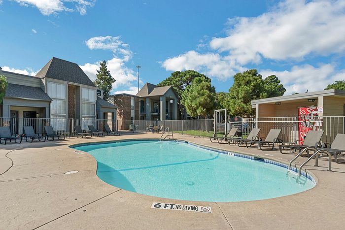 Community pool with sun chairs in front of apartments
