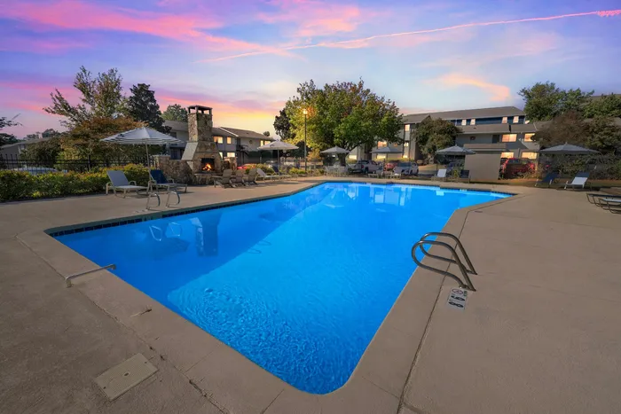 Relaxing pool area at night time with lounge chairs at Eagles West Apartments in Auburn, AL, featuring outdoor amenities.