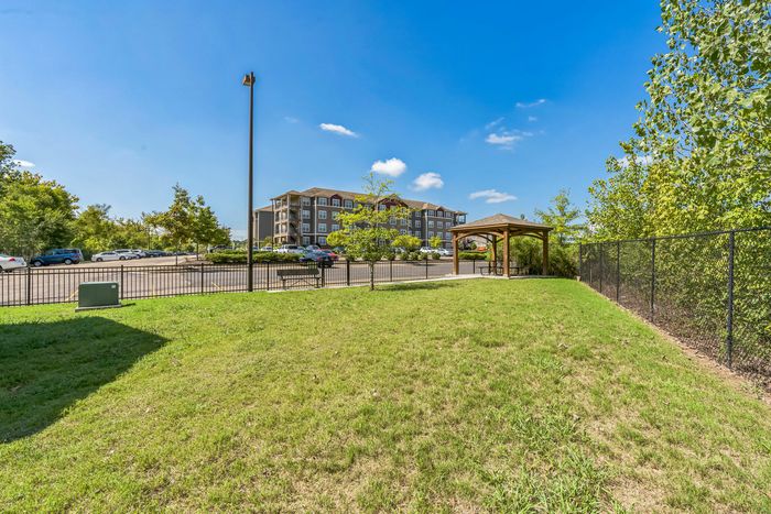 Fenced-in pet park with bench and shaded gazebo for seating