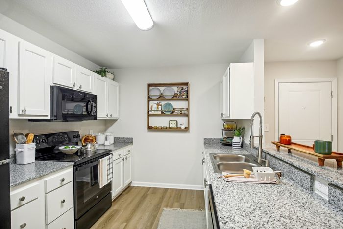 Modern kitchen with granite countertops, white cabinetry, black appliances, and a cozy dining area at our Murfreesboro apartments