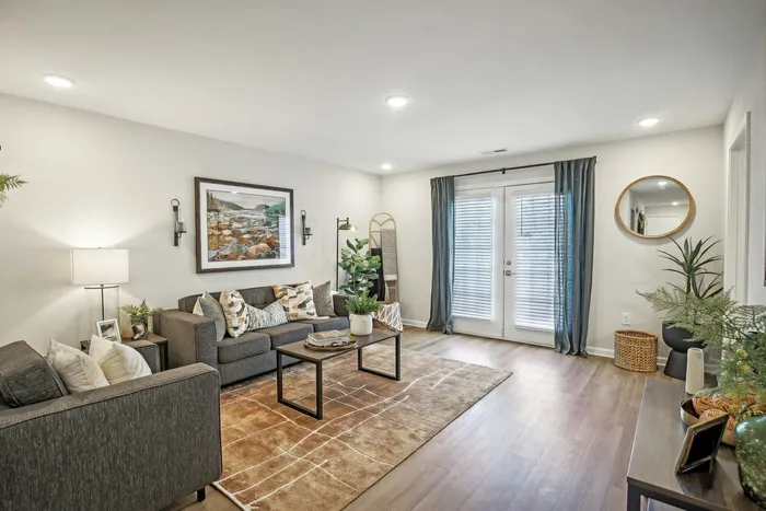 Cozy living room with modern furniture, decorative wall art, and wood-style flooring at The Preserve Murfreesboro apartments.