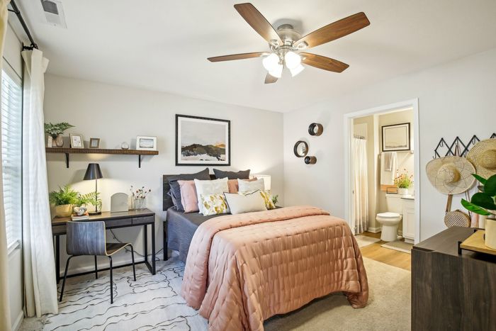 Spacious bedroom with neutral walls, soft carpeting, and an en-suite bathroom at The Preserve Murfreesboro apartments.