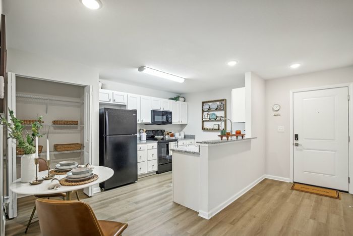 Open kitchen with white cabinetry, black appliances, granite countertops, and a pantry at The Preserve Murfreesboro apartments.