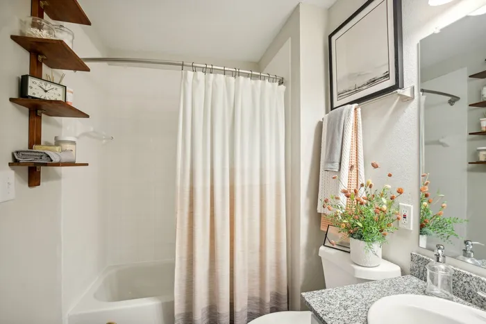 Modern bathroom with granite countertops, white cabinetry, and a shower-tub combination at The Preserve Murfreesboro apartments.