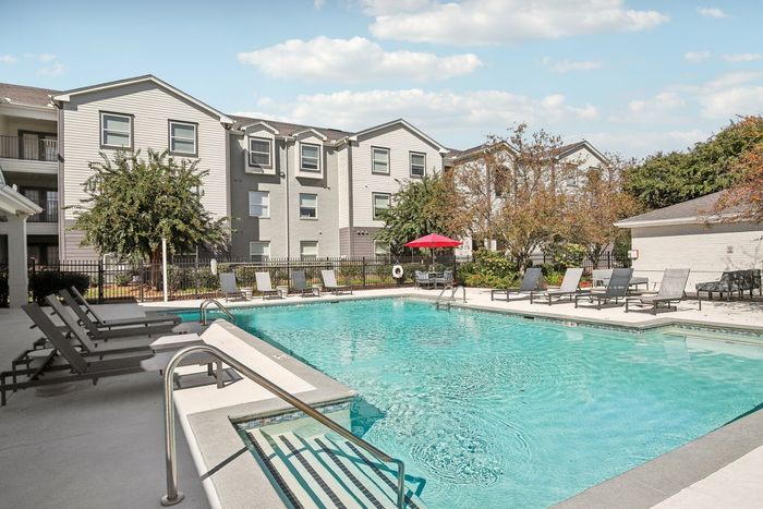Outdoor pool with lounge chairs, shaded seating, and a nearby clubhouse at The Preserve Murfreesboro.