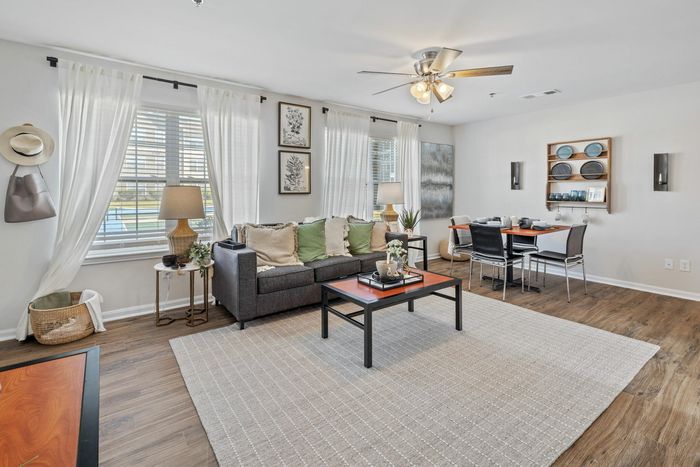 Spacious living room with curtains and wood-style flooring at Theater Street Apartments in Lafayette, LA