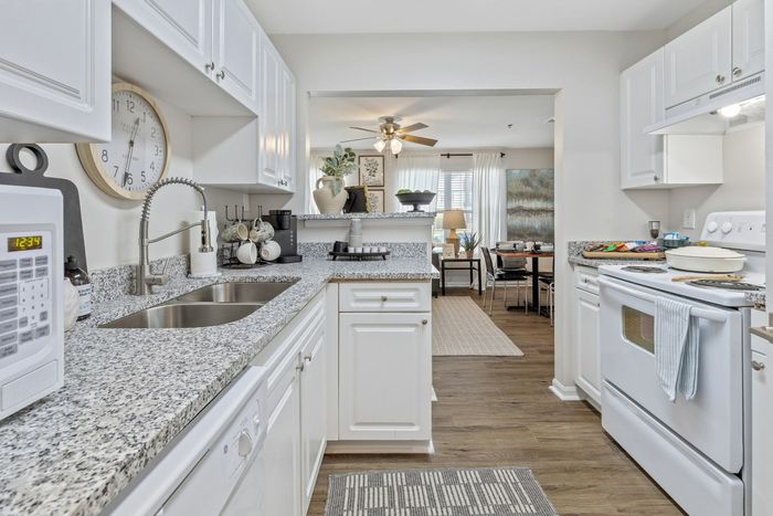 Kitchen with white cabinets and grey granite counters at Theater Street Apartments in Lafayette, LA