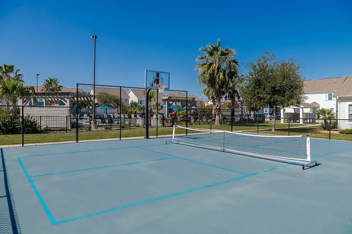 Inviting pickleball and basketball court amidst lush greenery in a vibrant community setting.