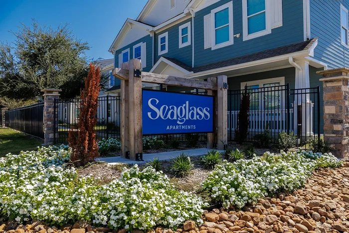 Charming Seaglass Apartments entrance surrounded by vibrant landscaping and modern architecture.