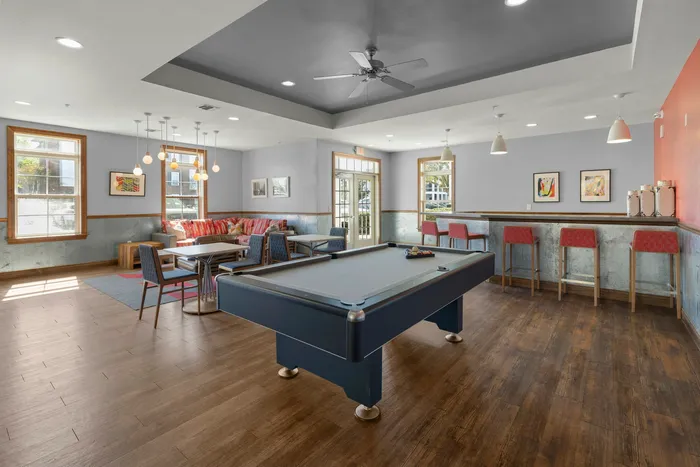 Inviting community lounge showcasing a modern billiards table, vibrant seating area, and stylish bar stools against a backdrop of chic decor and warm lighting.