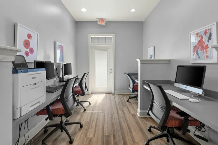 Modern workspace featuring multiple computer stations with sleek design, comfortable chairs, and stylish artwork on the walls.