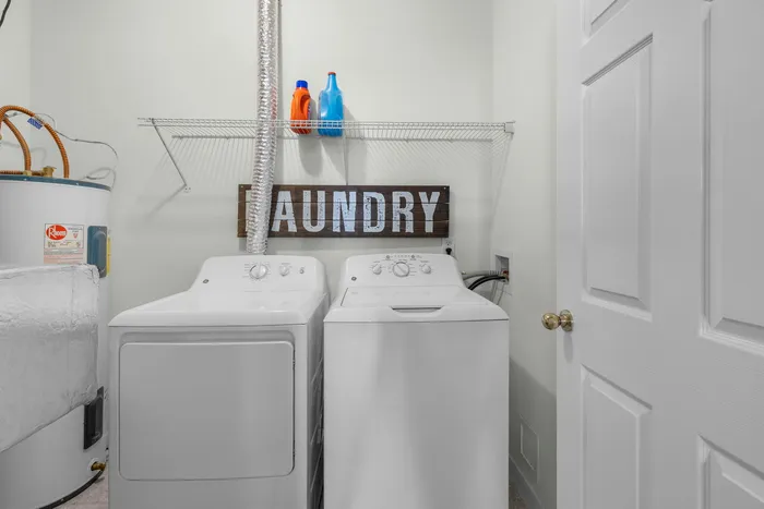 Modern laundry room with washer, dryer, and neatly organized shelf, offering convenient in-home amenities.