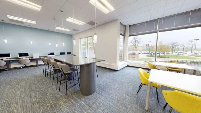 Modern, well-lit coworking space featuring sleek desks, comfortable chairs, and large windows offering expansive views.