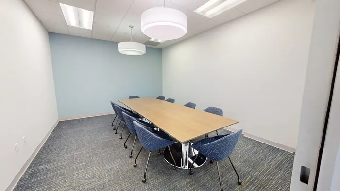 Modern conference room with a sleek wooden table, stylish chairs, and elegant lighting, ideal for productive meetings.