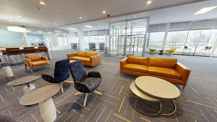 Modern business center lobby with stylish seating, spacious layout, and floor-to-ceiling windows providing natural light.